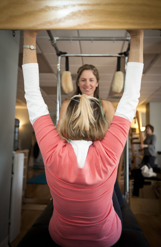 Heike Yates coaching a women over 50 in person on the Pilates Cadillac. 