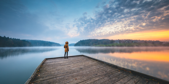 person standing on a dock at sunrise