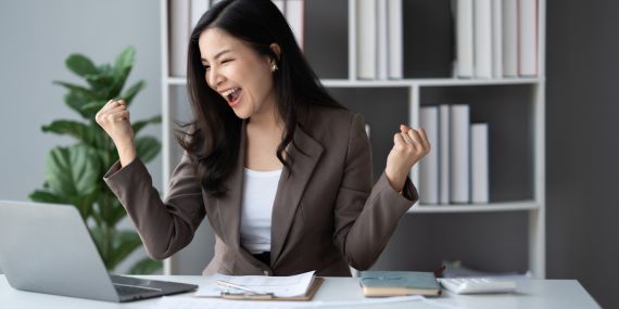 woman sitting at desk and celebrating