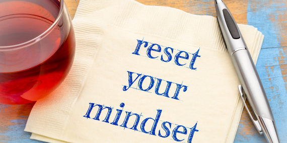 reset your mindset written on a napkin with a glass of wine and pen