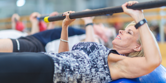 midlife woman doing a bench press in class