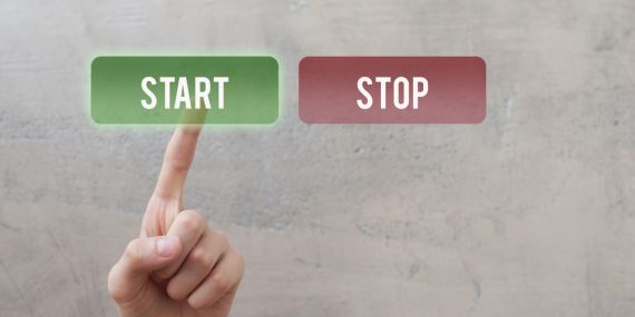 Stop starting over in midlife. A wall with a stop and start button and the person presses the green start button.