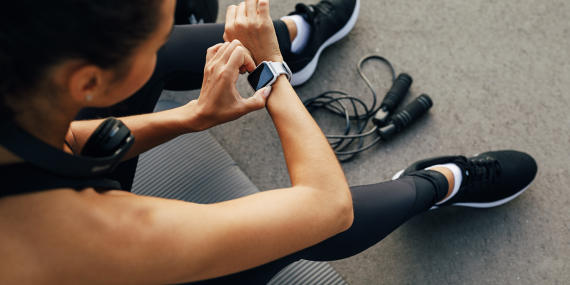 Woman reconsidering familiar fitness routines. Woman checking her workout watch in the gym.