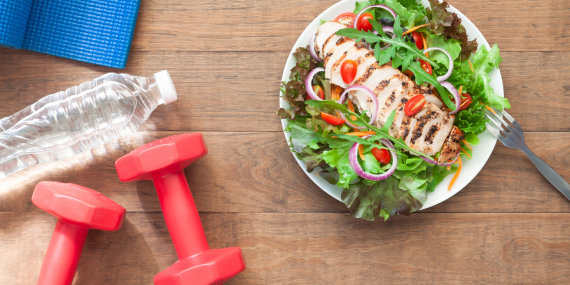 Healthy aging and fitness habits. A plate with healthy foods, weights and a water bottle.