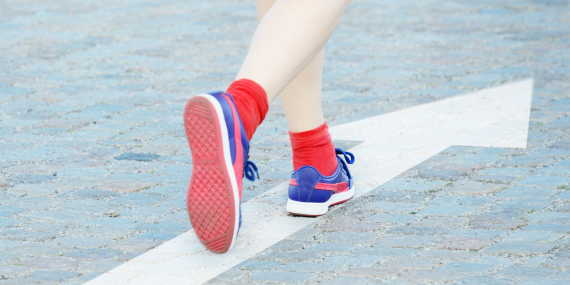 Feet walking on a white arrow towards fitness choices. 